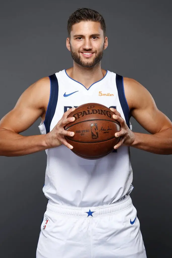 Professional basketball player in uniform holding a basketball during a studio portrait session.