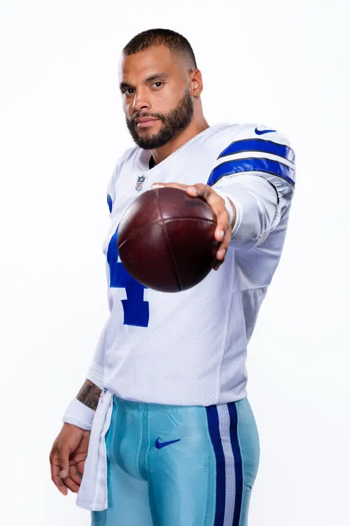 Professional football quarterback in uniform holding a football during a studio portrait session.