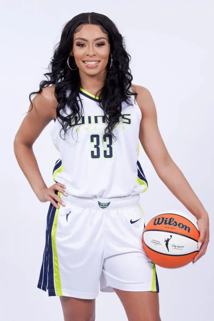 Professional women's basketball player in uniform holding a basketball for a studio portrait.