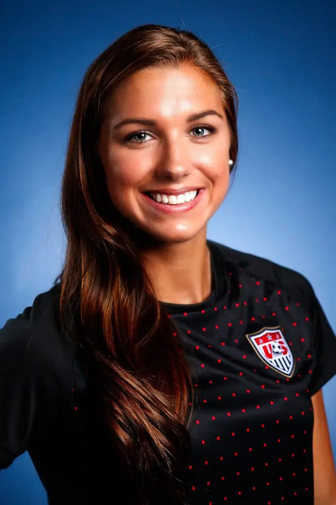 Professional women's soccer player photographed in uniform against a blue studio background.