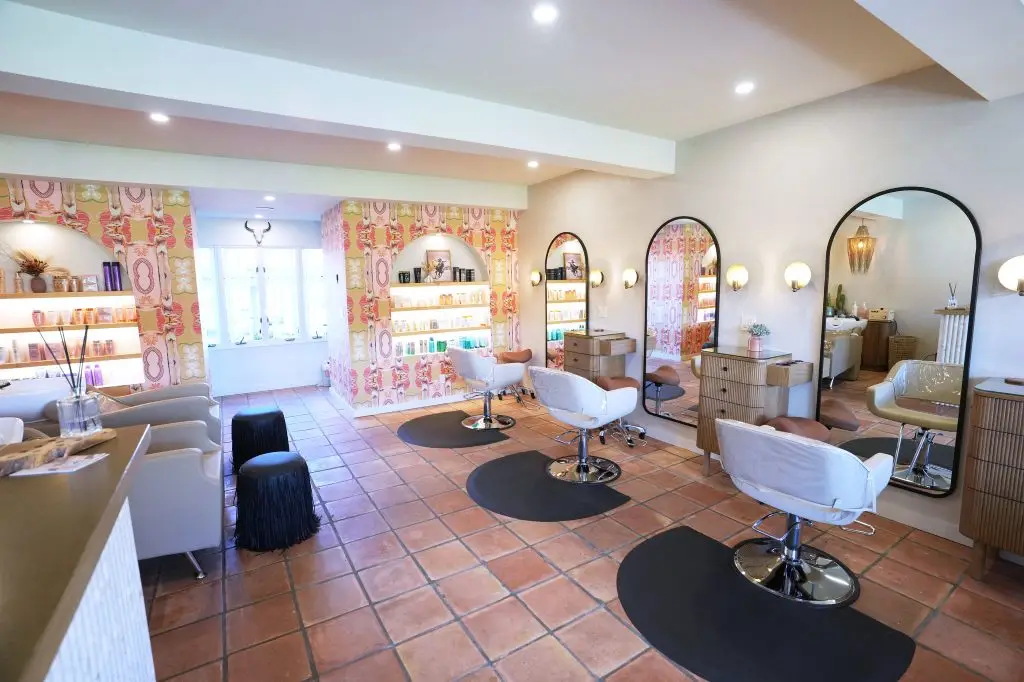 Salon interior with white styling chairs, arched mirrors, and terracotta tile flooring