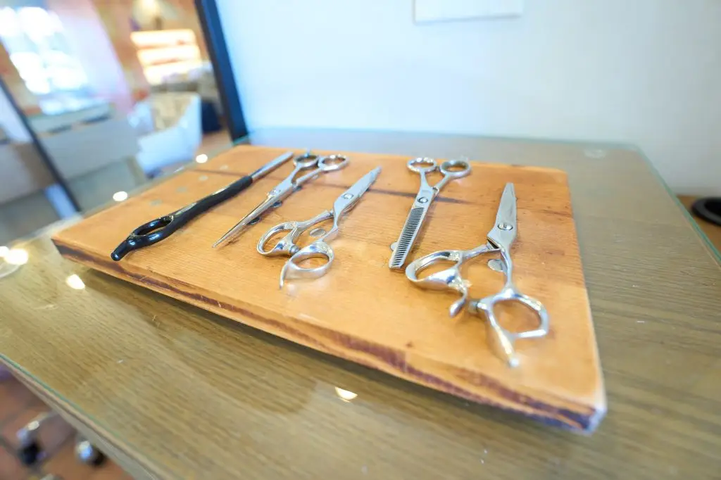 Professional styling shears arranged on a wooden board at a salon station