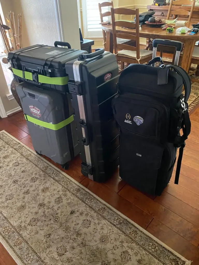 Rolling cases and equipment bags containing a compact professional headshot studio packed for travel